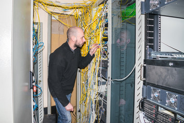 The engineer connects the optical wire to the central router. The system administrator works in the server room of the data center. The network engineer is next to the server racks