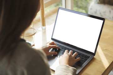 Women using laptop with blank screen at table in the office.