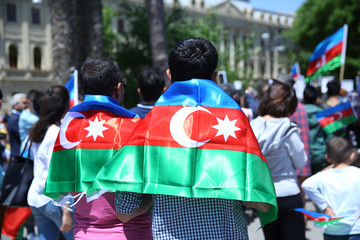 The Azerbaijani flag is on the background of the city . Action . Azerbaijan flag in Baku, Azerbaijan. National sign background. The boy put a flag on his shoulder.