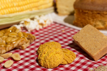Delicious yellow cookie of corn. Sweet food of Festa Junina, a typical brazilian party. Red plaid fabric on table.