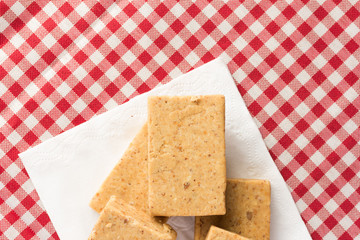 Pacoca is a candy with peanuts from Brazil. Sweet food of Festa Junina, a typical brazilian party. Snack on napkin, red plaid table.