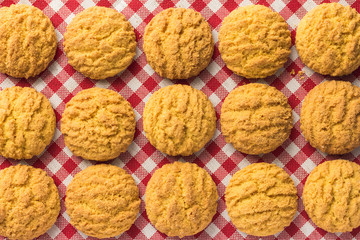 Delicious yellow cookie of corn. Sweet food of Festa Junina, a typical brazilian party. Candy aligned on red plaid table.