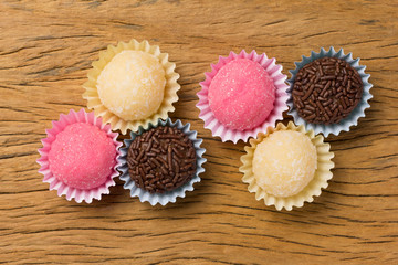 Brigadeiro Beijinho and Bicho de pé: sweets from Brazil. Child birthday party. Overhead of candy ball on rustic wood table.