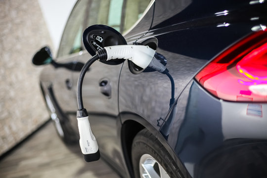 White Charging Adapter Cable Pluged In A Blue Hybrid Sports Car