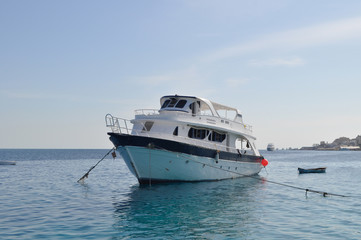 Fototapeta na wymiar Yacht and azure coast with white sand, clean and clear blue water on a sunny day