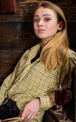 Girl student relaxing with glass of mulled wine, close up. Lady on dreamy face in plaid clothes looks casual. Girl in casual outfit sits in wooden vintage interior. Relaxation concept