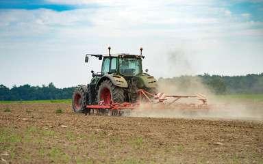 Obraz premium tracteur en activité d'aération du sol dans le champ la poussière vole