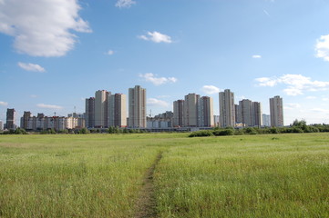 Fototapeta na wymiar high residential buildings on the background of a large field and a blue sky