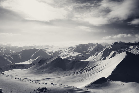 Fototapeta Black and white snowy mountains and sunlight off-piste slope