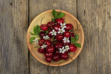 red cherries in wooden plate on wooden background