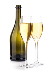 Two glasses of champagne on the background of brown bottles close-up isolated on a white.