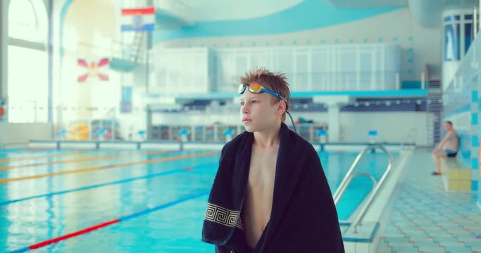 Young professional swimmer walks along the pool