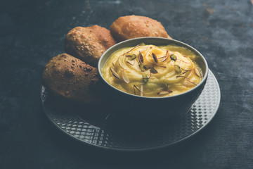 Shrikhand with fried Puri / Poori served in a bowl and plate over moody background. Selective focus