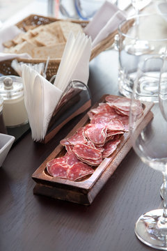 Salami in the wooden plate on the table