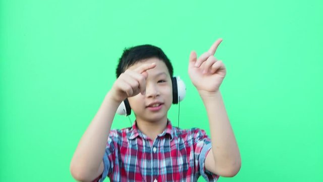 Young asian boy wearing hesdset and dancing in front of green screen 