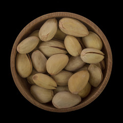 pistachio in wooden cup isolated on black background. top view