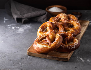 Freshly baked homemade soft pretzel with salt on rustic table. Perfect for Octoberfest.  - obrazy, fototapety, plakaty