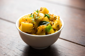 Chatpate Masala Aloo Sabzi fry OR Bombay potatoes served in a bowl, selective focus