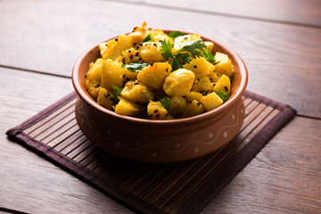 Chatpate Masala Aloo Sabzi fry OR Bombay potatoes served in a bowl, selective focus