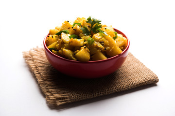 Chatpate Masala Aloo Sabzi fry OR Bombay potatoes served in a bowl, selective focus