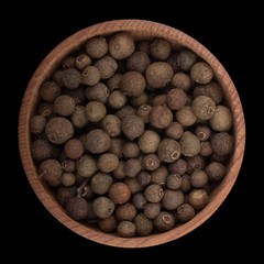 allspice in wooden cup isolated on black. top view