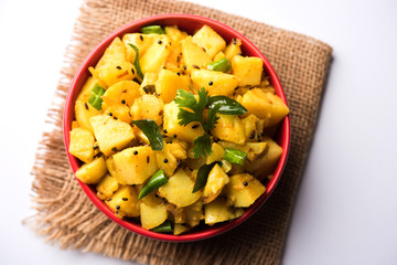 Chatpate Masala Aloo Sabzi fry OR Bombay potatoes served in a bowl, selective focus