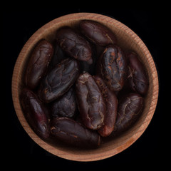 cacao in wooden cup isolated on black. top view