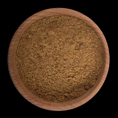 ground nutmeg in wooden cup isolated on black. top view