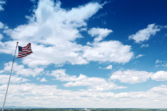 American Flag against Blue Sky and Mountains.