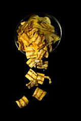 Potato chips in glass bowl on black background