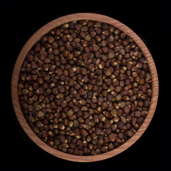 Maniquette pepper in wooden cup isolated on black. top view
