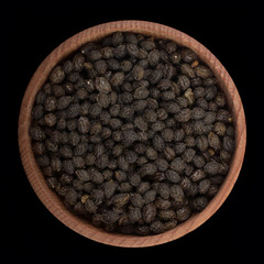 seeds of pawpaw in wooden cup isolated on black. top view