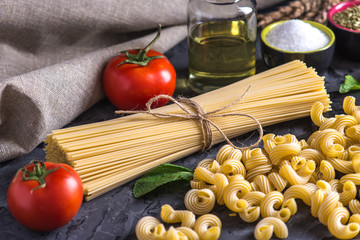 Uncooked pasta cavatappi and spaghetti with ingredients for tomato sauce. Concept of the composition of food design.