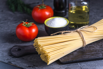 Uncooked pasta spaghetti with ingredients for tomato sauce. Concept of the composition of food design.