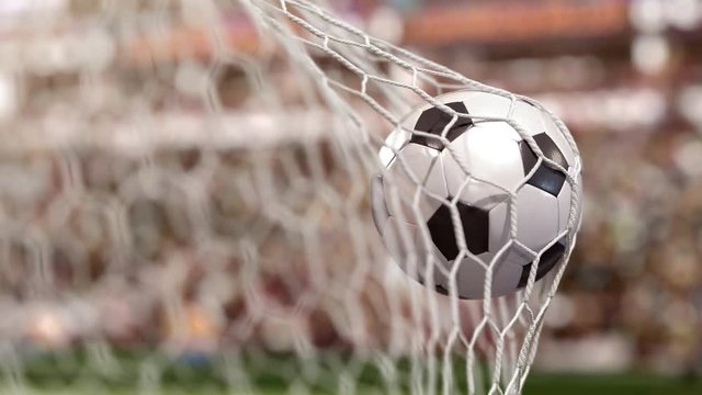 Beautiful soccer ball flies into the net of the gate in the stadium filled with spectators. The movement at the beginning is accelerated then slowly
