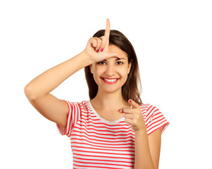 a happy woman gives a sign of the loser on his forehead, looking at you and pointing his finger at...