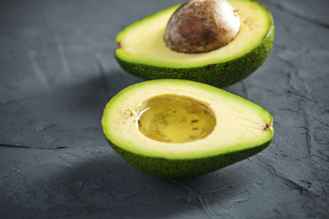 Oil flowing from the avocado fruit cut in half on dark background. Organic eco products for food...