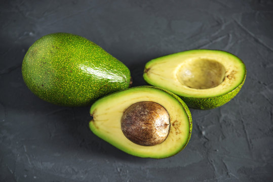 Avocado fruit cut in half on the dark background. Concept organic eco products for food and cosmetic procedures