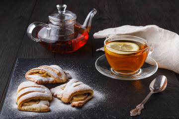 Cottage cheese cookies with apple on plate with tea on dark wooden table
