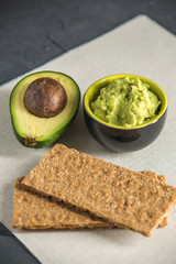 Cold appetizer of mashed avocado flesh with bread on the table. Traditional mexican food from organic eco products