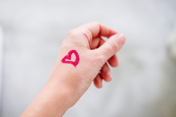 Heart drawn with lipstick on woman's hand