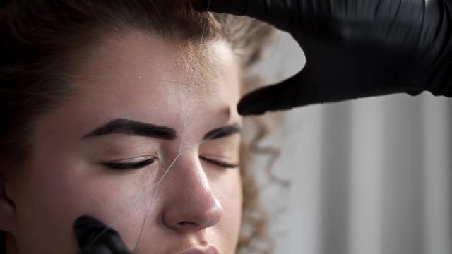 Removing small hairs from face with thread in beauty salon, depilation with thread, threading in beauty salon, facial treatment, cosmetic manipulations