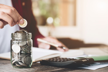 business man saving money with putting coin in glass and calculating for financial saving, finance accounting concept