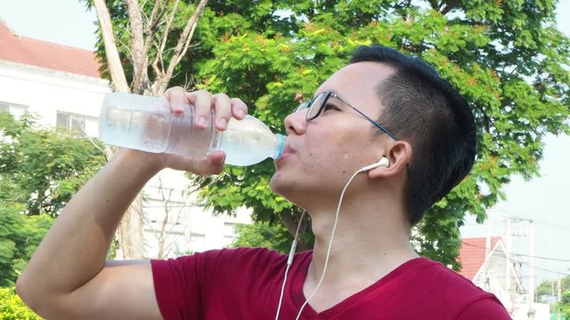 Young asian man drinking water after jogging 