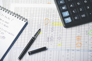 Tables with accounting figures, pen, paper notebook and calculator, top view