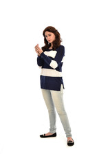  full length portrait of girl wearing striped blue and white jumper and jeans. standing pose on white studio background