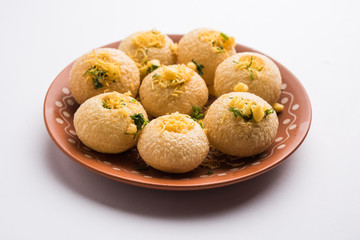 Stuffed Sev Puri is a popular Indian roadside chat item, served in a white plate. Top view, selective focus