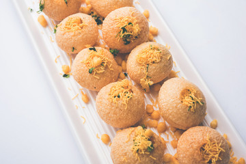 Stuffed Sev Puri is a popular Indian roadside chat item, served in a white plate. Top view, selective focus