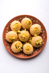 Stuffed Sev Puri is a popular Indian roadside chat item, served in a white plate. Top view, selective focus