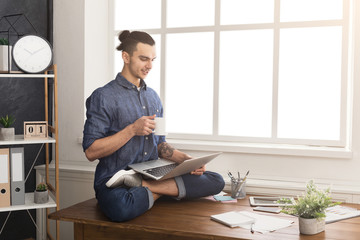 Flexible man practicing yoga at workplace